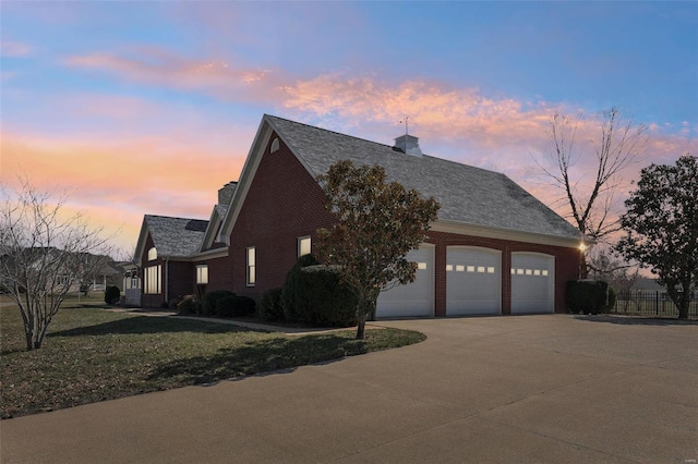 900 Deer Circle Dr, Carlyle, IL 62231 - view of home's exterior with concrete driveway, a chimney, brick siding, a lawn, and an attached garage
