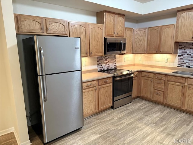 2 Monarch Trace Ct Unit 103, Chesterfield, MO 63017 - kitchen featuring appliances with stainless steel finishes, light wood finished floors, backsplash, and light countertops