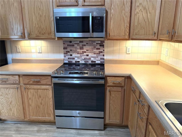 2 Monarch Trace Ct Unit 103, Chesterfield, MO 63017 - kitchen featuring stainless steel appliances, backsplash, a sink, and light countertops