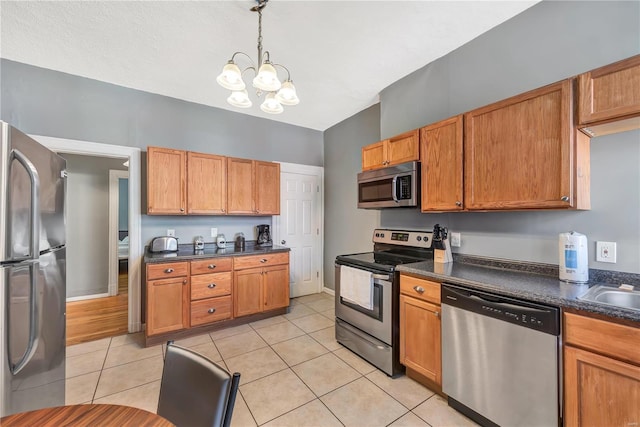 2107 Russell Blvd, Saint Louis, MO 63104 - kitchen featuring appliances with stainless steel finishes, dark countertops, a chandelier, light tile patterned floors, and decorative light fixtures