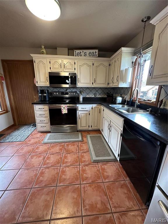 417 Carriage Pl, Lebanon, MO 65536 - kitchen with appliances with stainless steel finishes, cream cabinets, a sink, tasteful backsplash, and dark countertops