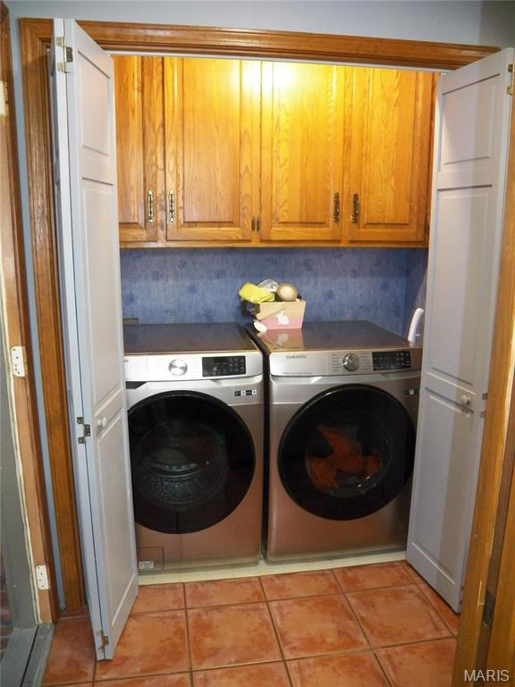 417 Carriage Pl, Lebanon, MO 65536 - laundry room featuring cabinet space, washing machine and dryer, and light tile patterned flooring