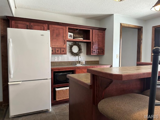14348 Hidden Trails Cir, Dexter, MO 63841 - kitchen featuring freestanding refrigerator, a kitchen bar, open shelves, dark countertops, and a textured ceiling