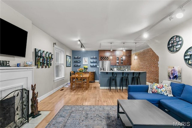 4486 Laclede Ave Unit 4486, Saint Louis, MO 63108 - living room featuring rail lighting, light wood finished floors, a fireplace with flush hearth, and baseboards