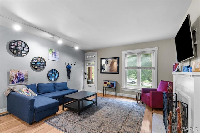 4486 Laclede Ave Unit 4486, Saint Louis, MO 63108 - living area featuring light wood-style flooring, rail lighting, a fireplace with flush hearth, and baseboards