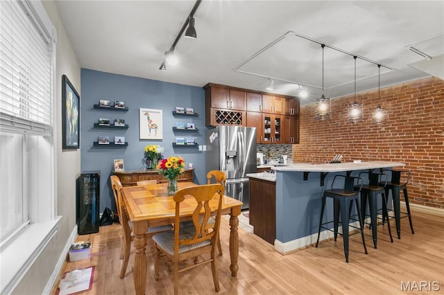 4486 Laclede Ave Unit 4486, Saint Louis, MO 63108 - dining room featuring rail lighting, light wood finished floors, brick wall, and baseboards