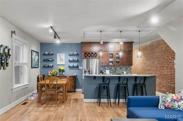4486 Laclede Ave Unit 4486, Saint Louis, MO 63108 - kitchen featuring stainless steel refrigerator with ice dispenser, a breakfast bar, track lighting, light countertops, and light wood-type flooring