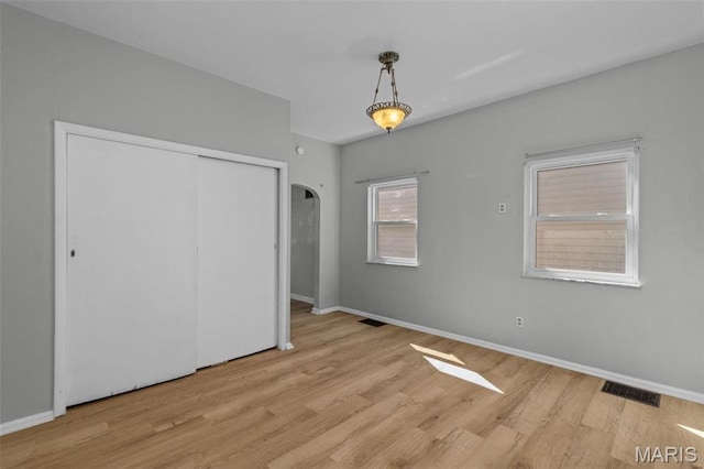 5331 Arsenal St, Saint Louis, MO 63139 - unfurnished bedroom featuring arched walkways, wood finished floors, baseboards, and a closet