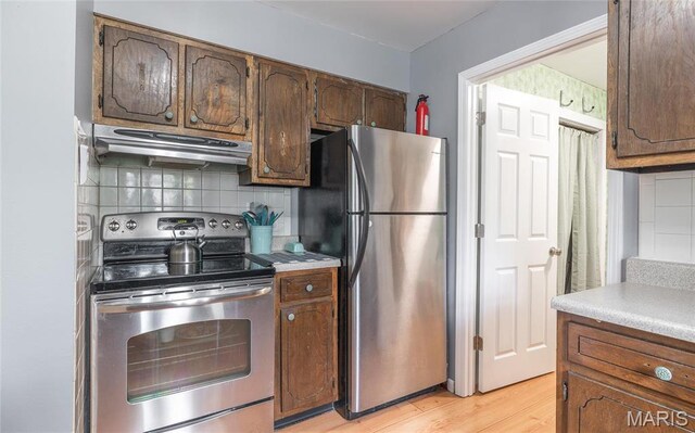 400 S Hickory St, Salem, MO 65560 - kitchen featuring appliances with stainless steel finishes, extractor fan, light wood-type flooring, tasteful backsplash, and light countertops