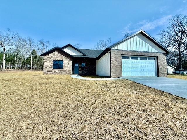 single story home with an attached garage, driveway, brick siding, board and batten siding, and a front yard