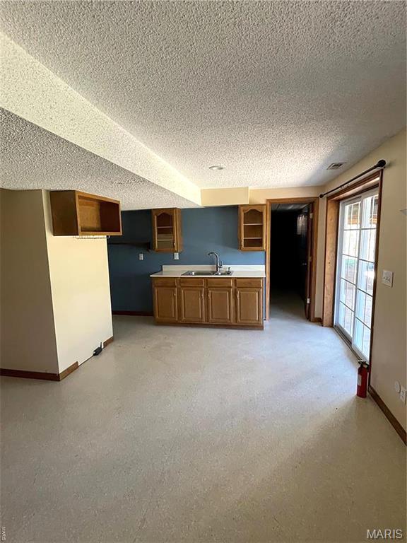 22 Coachman Ln, Villa Ridge, MO 63089 - kitchen with a sink, baseboards, a textured ceiling, brown cabinets, and light countertops
