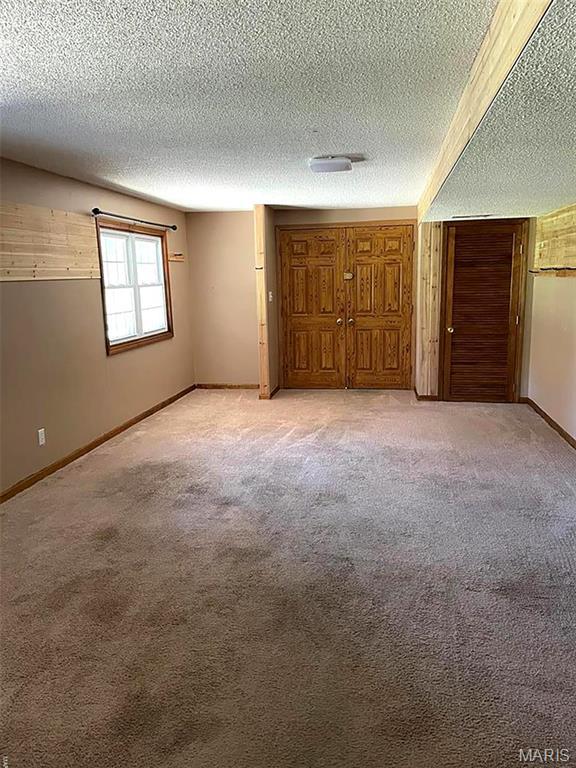22 Coachman Ln, Villa Ridge, MO 63089 - unfurnished bedroom featuring a textured ceiling, light colored carpet, and baseboards