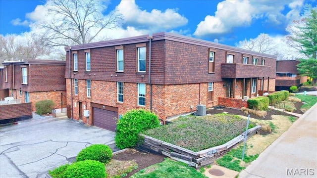 13515 Coliseum Dr Unit A, Chesterfield, MO 63017 - view of home's exterior featuring an attached garage, driveway, brick siding, mansard roof, and cooling unit