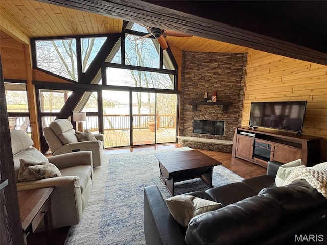 living area with plenty of natural light, a fireplace, wooden walls, wooden ceiling, and beam ceiling