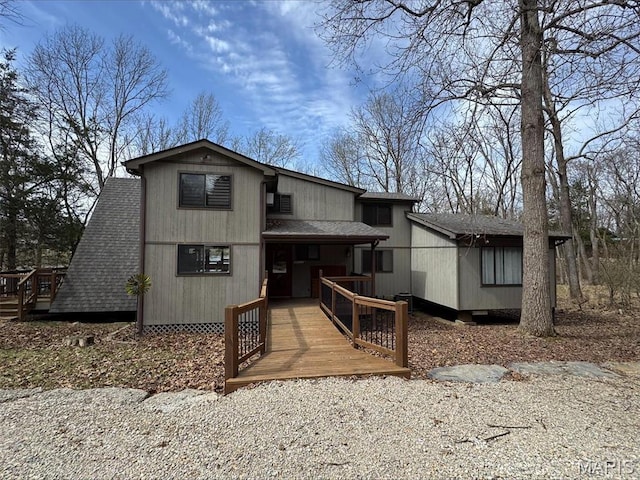 rear view of house with roof with shingles and a deck