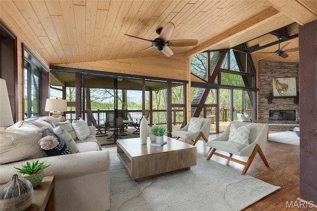 living room with ceiling fan, wood ceiling, healthy amount of natural light, a stone fireplace, and high vaulted ceiling