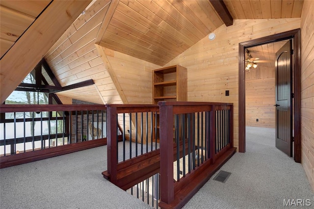 hall with wooden walls, carpet flooring, an upstairs landing, and wooden ceiling