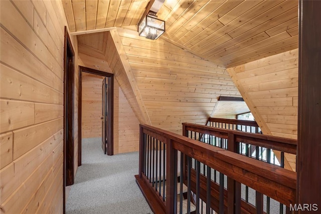 hallway with wooden ceiling, lofted ceiling, wood walls, and carpet flooring