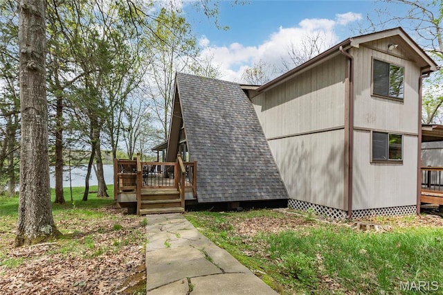 view of home's exterior featuring a deck with water view and roof with shingles