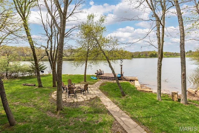 view of green lawn with a water view and a floating dock