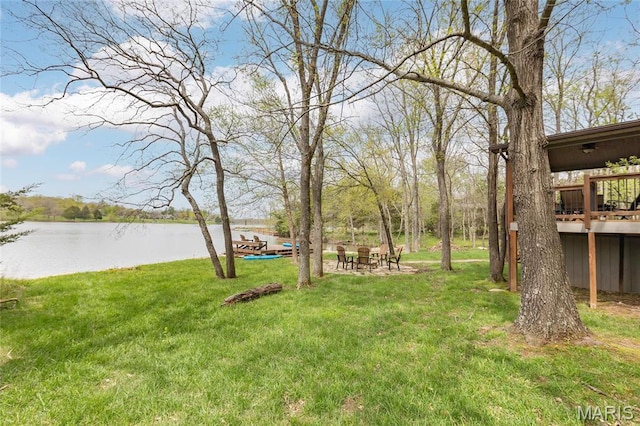 view of green lawn featuring a deck with water view