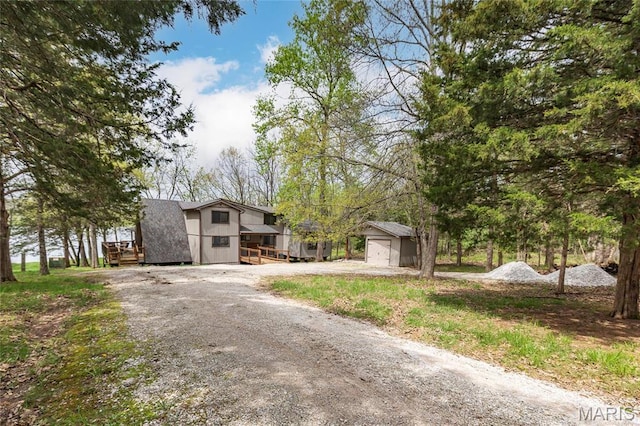 view of front facade featuring dirt driveway and an outbuilding
