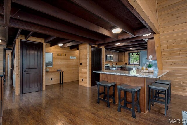 803 S Aspen Point Dr, Innsbrook, MO 63390 - kitchen featuring appliances with stainless steel finishes, wood walls, beamed ceiling, dark wood finished floors, and a breakfast bar area