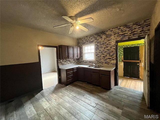 5052 Plover Ave, Saint Louis, MO 63120 - kitchen featuring light wood-style flooring, ceiling fan, light countertops, dark brown cabinetry, and a textured ceiling