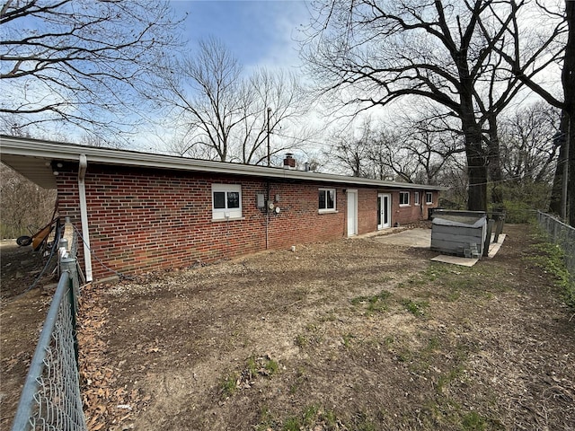 1227 Teson Rd, Hazelwood, MO 63042 - back of property with brick siding, fence, a chimney, and a jacuzzi