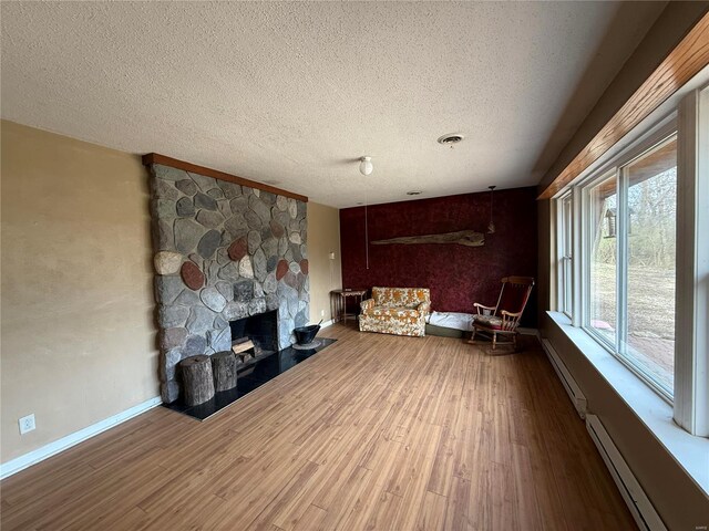 1227 Teson Rd, Hazelwood, MO 63042 - unfurnished living room with baseboard heating, a baseboard radiator, wood finished floors, a textured ceiling, and baseboards