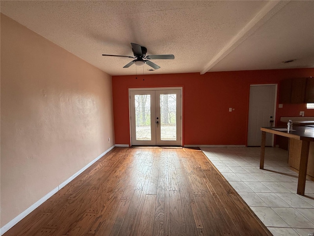 1227 Teson Rd, Hazelwood, MO 63042 - unfurnished living room with a ceiling fan, french doors, a textured ceiling, light wood-style flooring, and baseboards