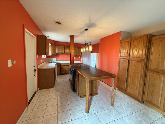 1227 Teson Rd, Hazelwood, MO 63042 - kitchen with black range with electric cooktop, freestanding refrigerator, brown cabinetry, tile counters, and a kitchen island