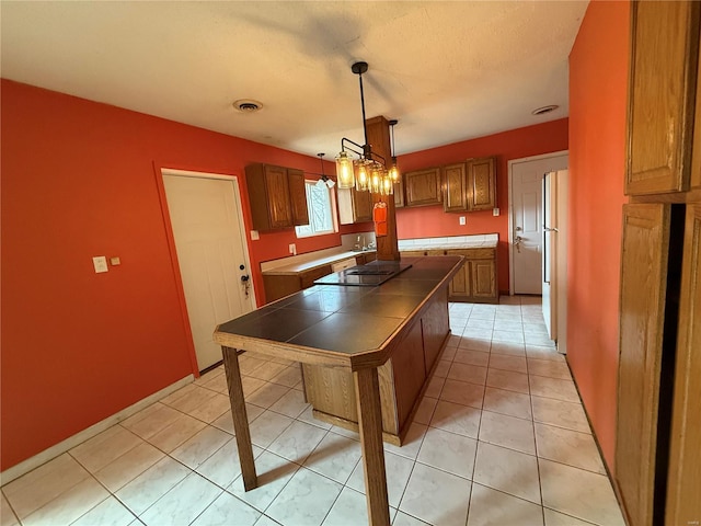 1227 Teson Rd, Hazelwood, MO 63042 - kitchen featuring tile counters, black electric cooktop, freestanding refrigerator, and brown cabinets