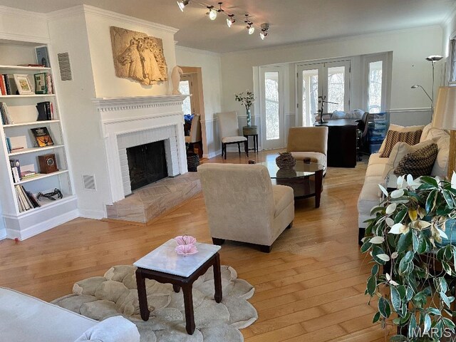 3921 Allenton Rd, Wildwood, MO 63069 - living room with ornamental molding, light wood-type flooring, built in shelves, a brick fireplace, and french doors