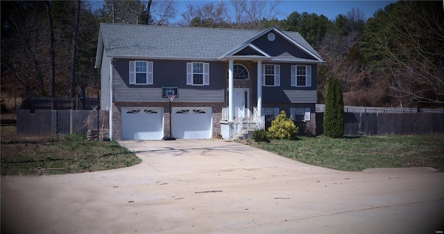 split foyer home with fence, concrete driveway, an attached garage, and brick siding