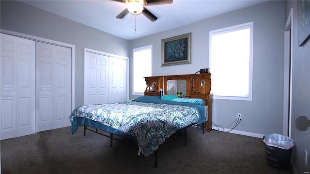 carpeted bedroom featuring multiple windows, multiple closets, and a ceiling fan