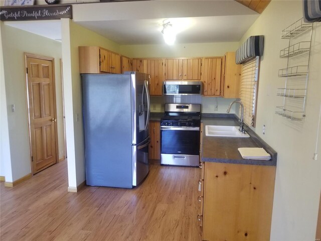 8774 E Chinquapin Ave E, Effingham, IL 62401 - kitchen with appliances with stainless steel finishes, a sink, dark countertops, light wood-style floors, and baseboards