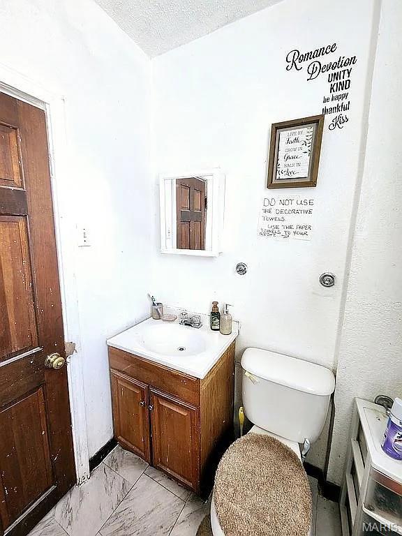 5244 Theodosia Ave, Saint Louis, MO 63113 - half bathroom with vanity, toilet, and marble finish floors