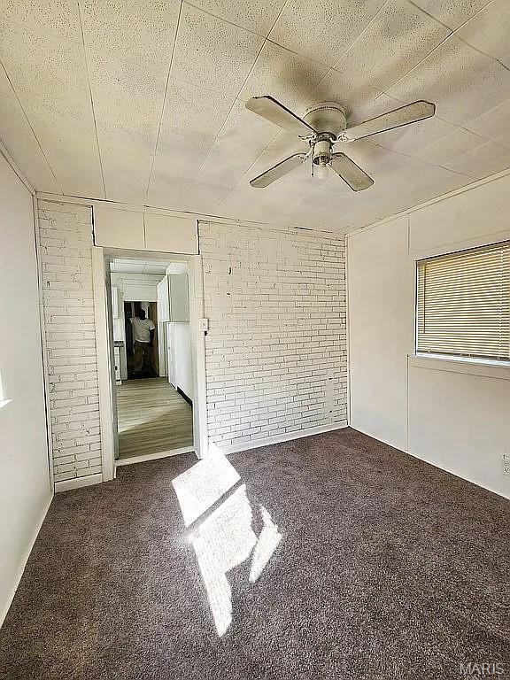 5244 Theodosia Ave, Saint Louis, MO 63113 - unfurnished bedroom featuring carpet floors, brick wall, and ceiling fan
