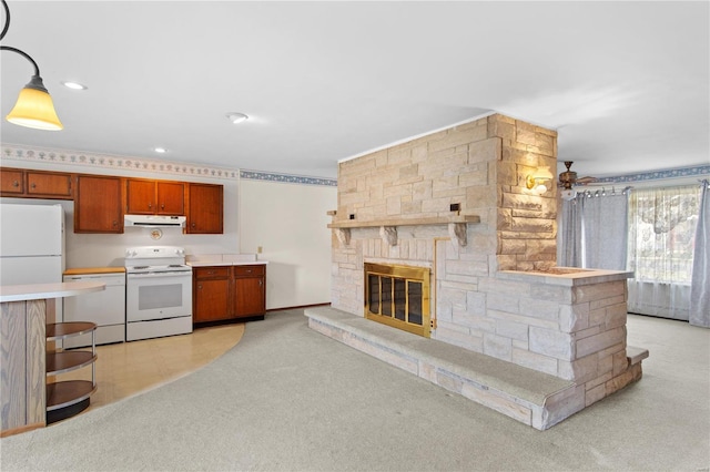 kitchen with white appliances, under cabinet range hood, a fireplace, light countertops, and light colored carpet
