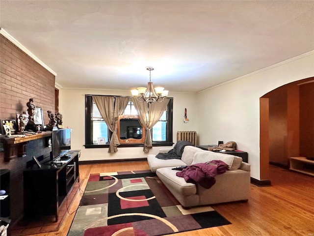 living area featuring arched walkways, light wood finished floors, a chandelier, ornamental molding, and baseboards