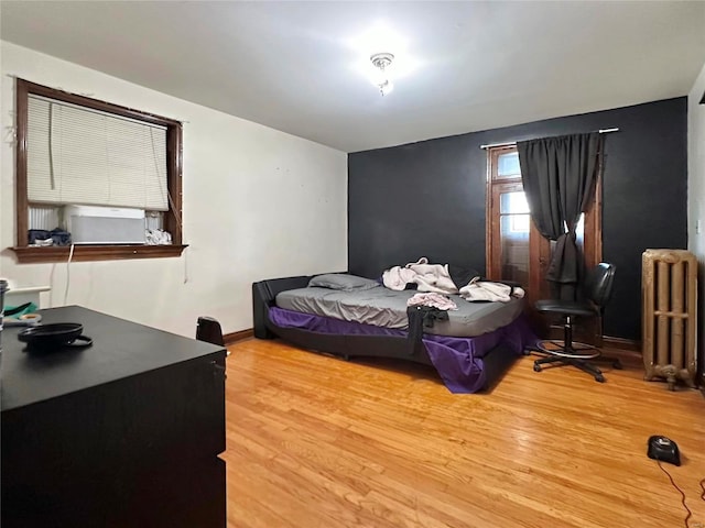 bedroom with radiator heating unit, light wood-style flooring, and baseboards