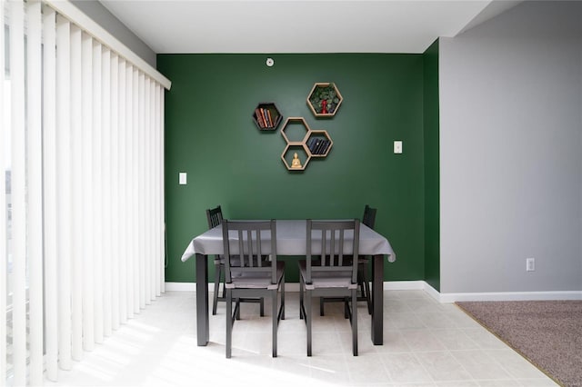 dining room featuring baseboards and an accent wall