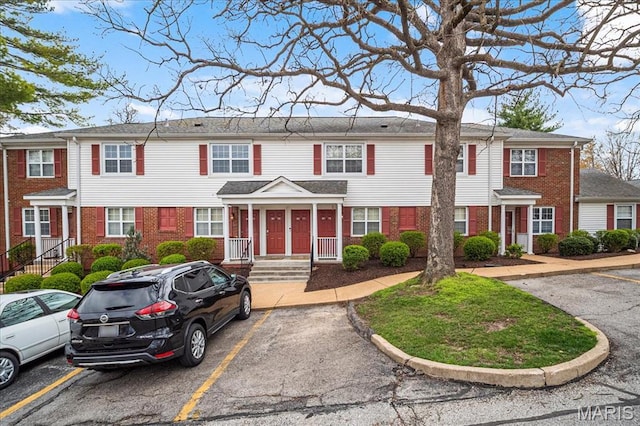 multi unit property with brick siding and uncovered parking