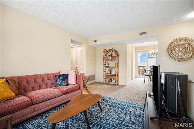 living room with a chandelier, carpet floors, a textured ceiling, and baseboards