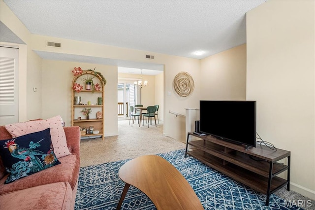 living area with a chandelier, carpet floors, a textured ceiling, and baseboards