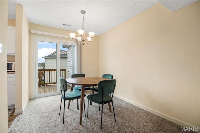 carpeted dining room featuring a chandelier, baseboards, and a textured ceiling
