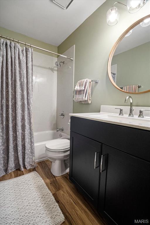 full bathroom with wood finished floors, vanity, toilet, and shower / bath combo with shower curtain