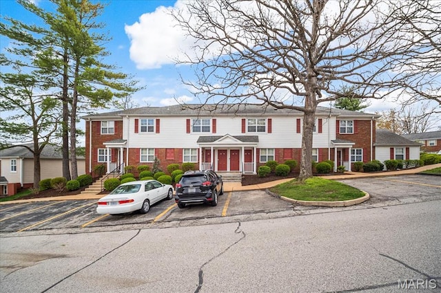 townhome / multi-family property with brick siding and uncovered parking
