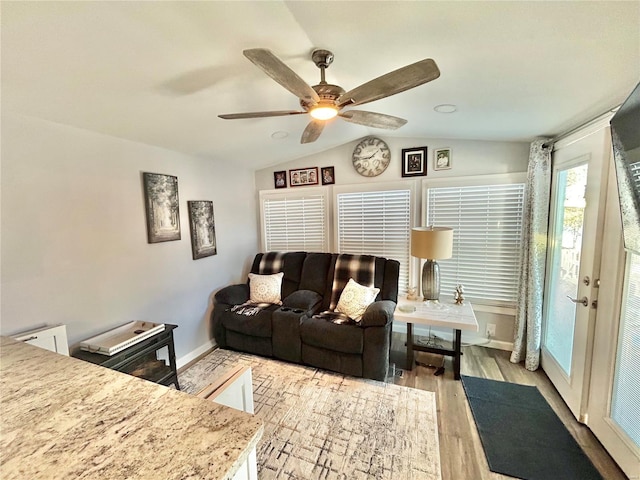 living area with lofted ceiling, a ceiling fan, baseboards, and light wood-type flooring